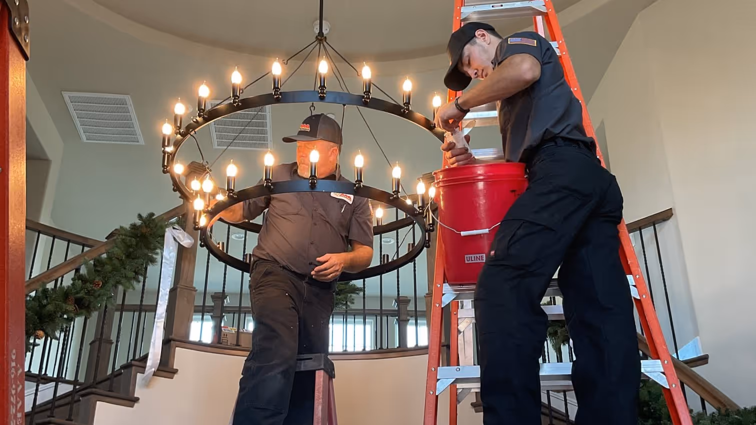 AAA technicians collaborating on a chandelier installation